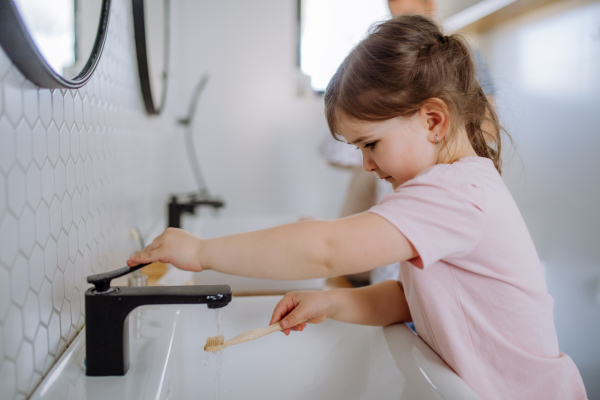 A little girl brushing her teeth in bathroom, morning routine concept.