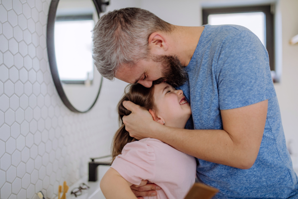 A father kissing his little daughter in bathroom.