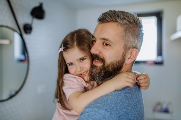 A happy father hugging his little daughter in bathroom.