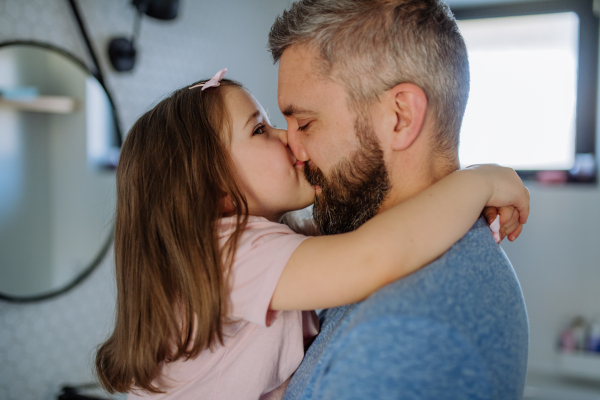 A father kissing his little daughter in bathroom.