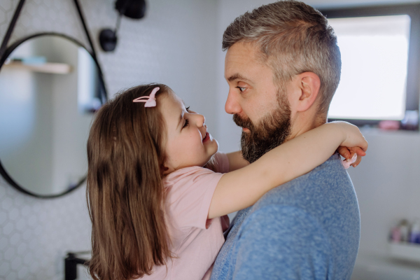 A happy father hugging his little daughter in bathroom.