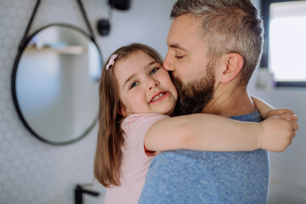 A father kissing his little daughter in bathroom.