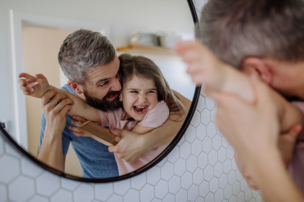 A father brushing his little daughter's hair in bathroom, morning routine concept.