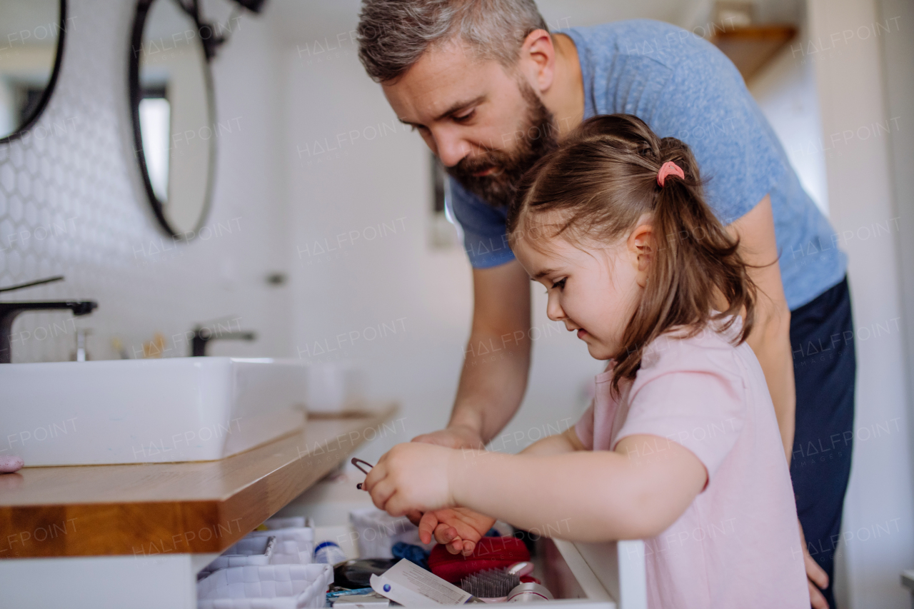 A happy father with his little daughter in bathroom, morning routine concept.