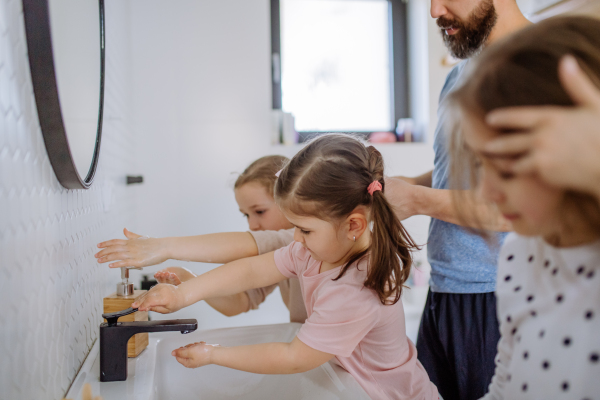 A father with three little children in bathroom, morning routine concept.