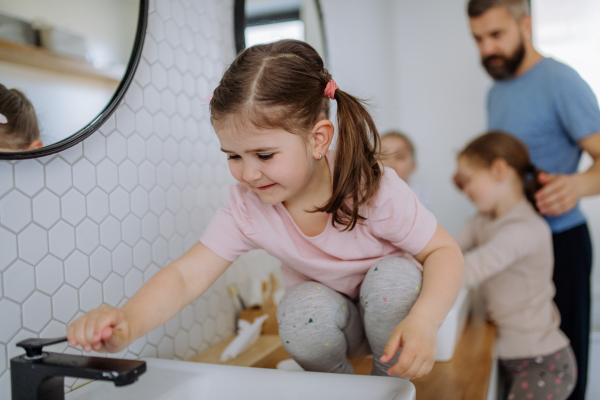 A father with three little children in bathroom, morning routine concept.