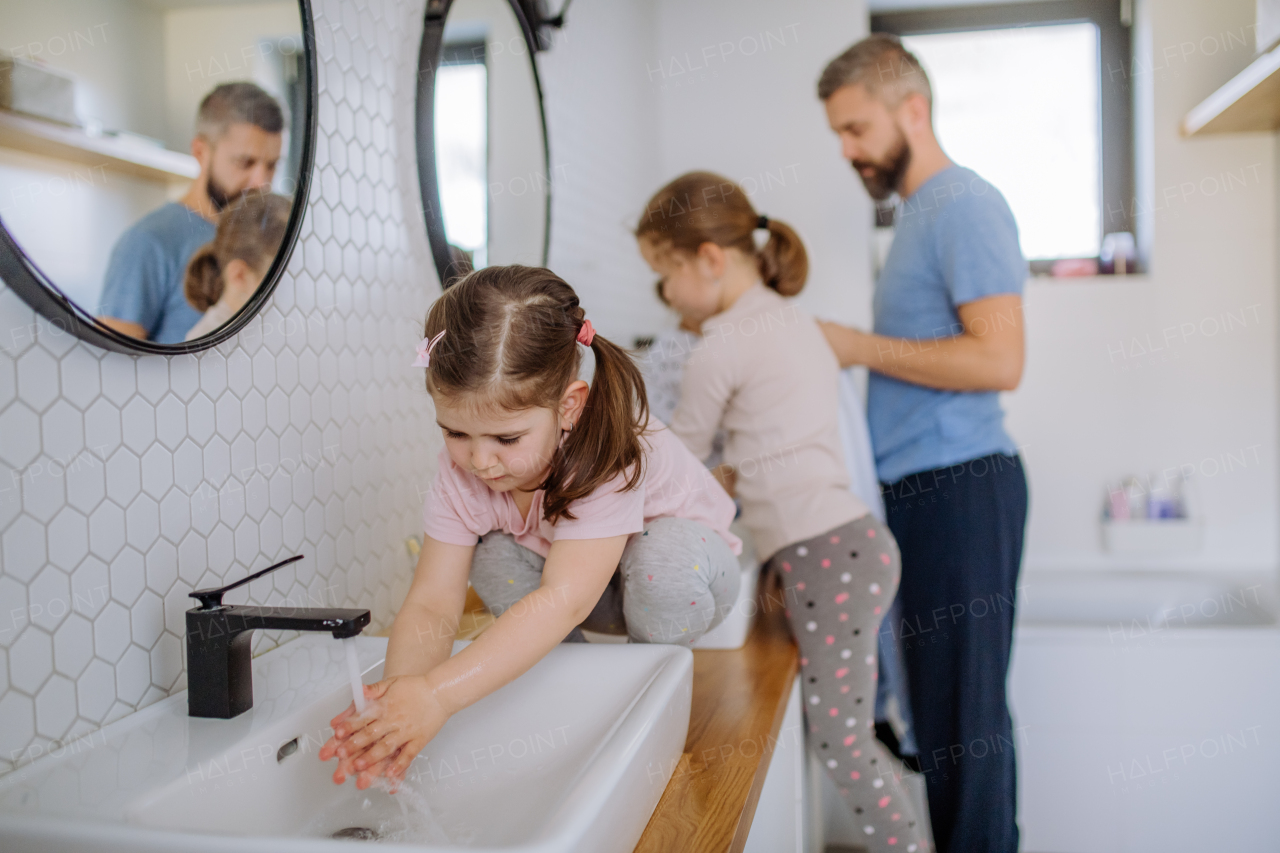 A father with three little children in bathroom, morning routine concept.