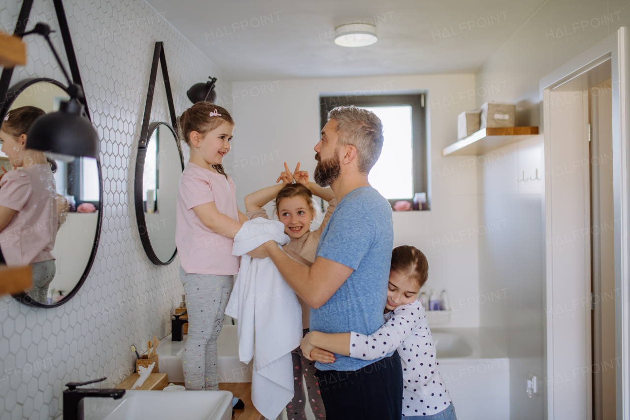 A father bonding with his three little daughters in bathroom, morning routine concept.