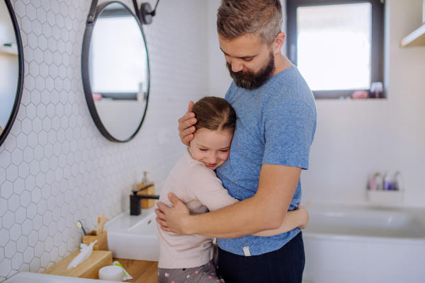 A happy father hugging his little daughter in bathroom.