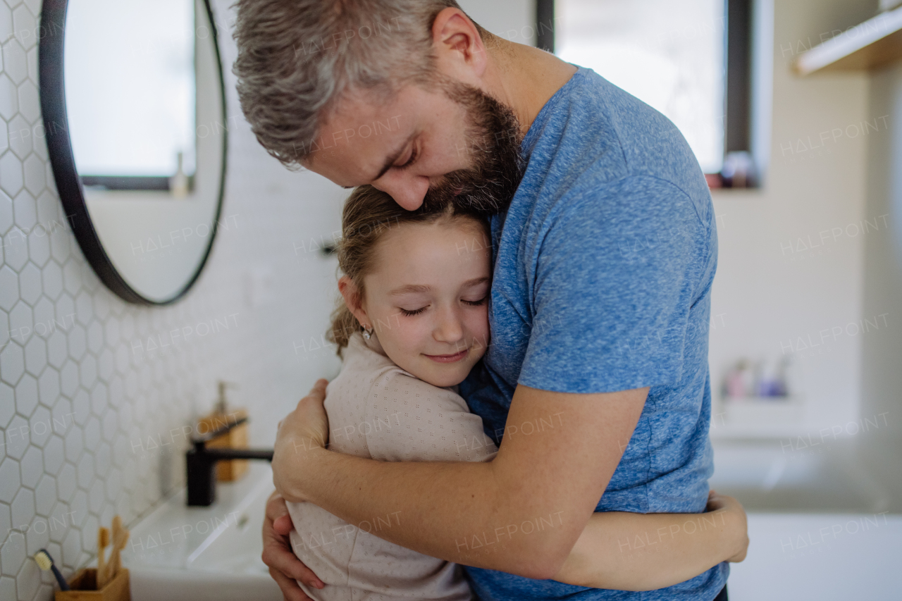 A father hugging his little daughter in bathroom.