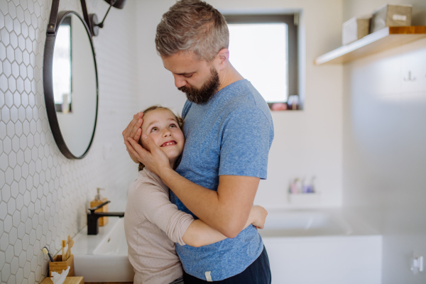 A happy father hugging his little daughter in bathroom.