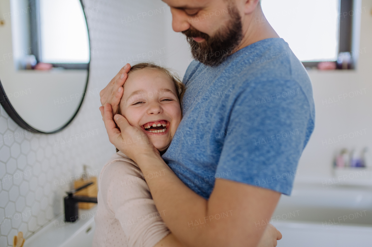 A happy father hugging his little daughter in bathroom.