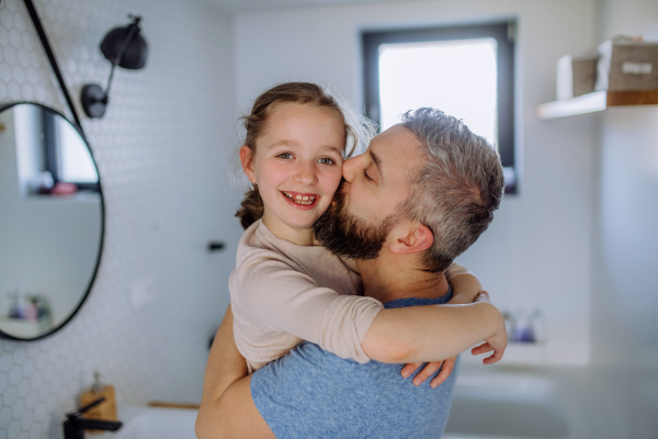 A father kissing his little daughter in bathroom.