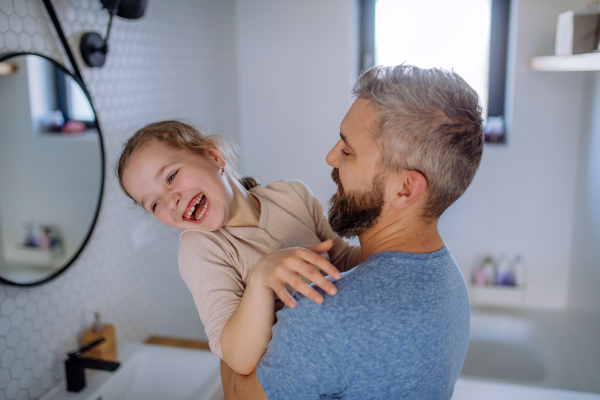 A happy father hugging his little daughter in bathroom.