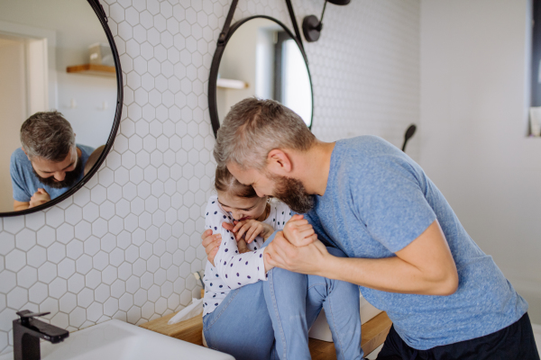 A happy father hugging his little daughter in bathroom.