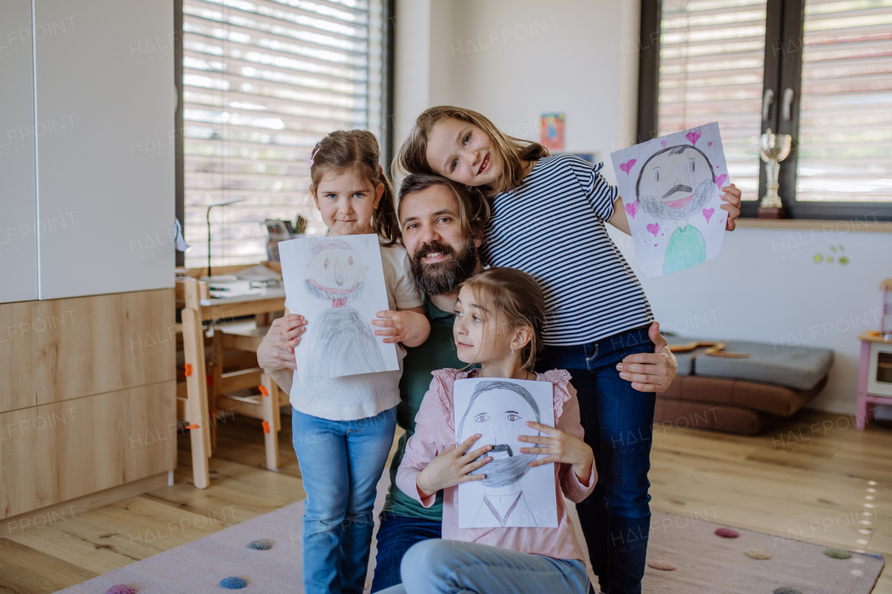 A father of three little daughters getting drawings from them at home.