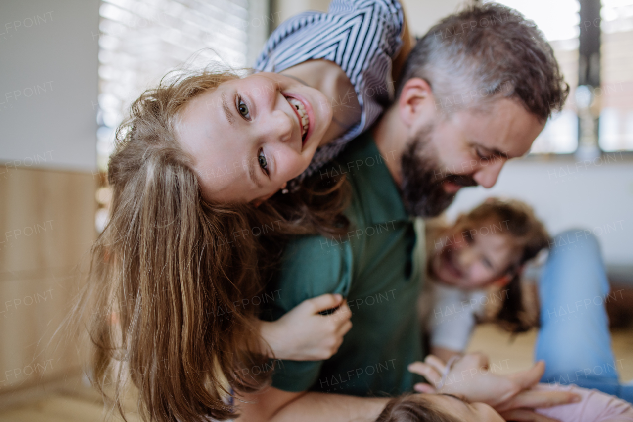 A cheerful father with three little daughters playing together at home.