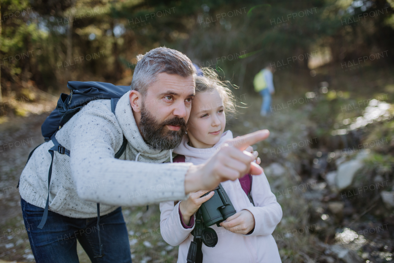 A father with small daughter with binoculars on walk in spring nature together.