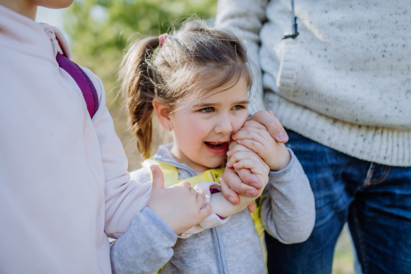 A father and little daughters hold hands on walk in nature.