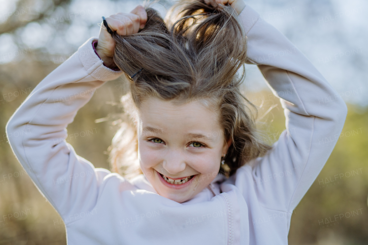 A funny portrait of pretty child girl standing in summer park looking in camera smiling happily.