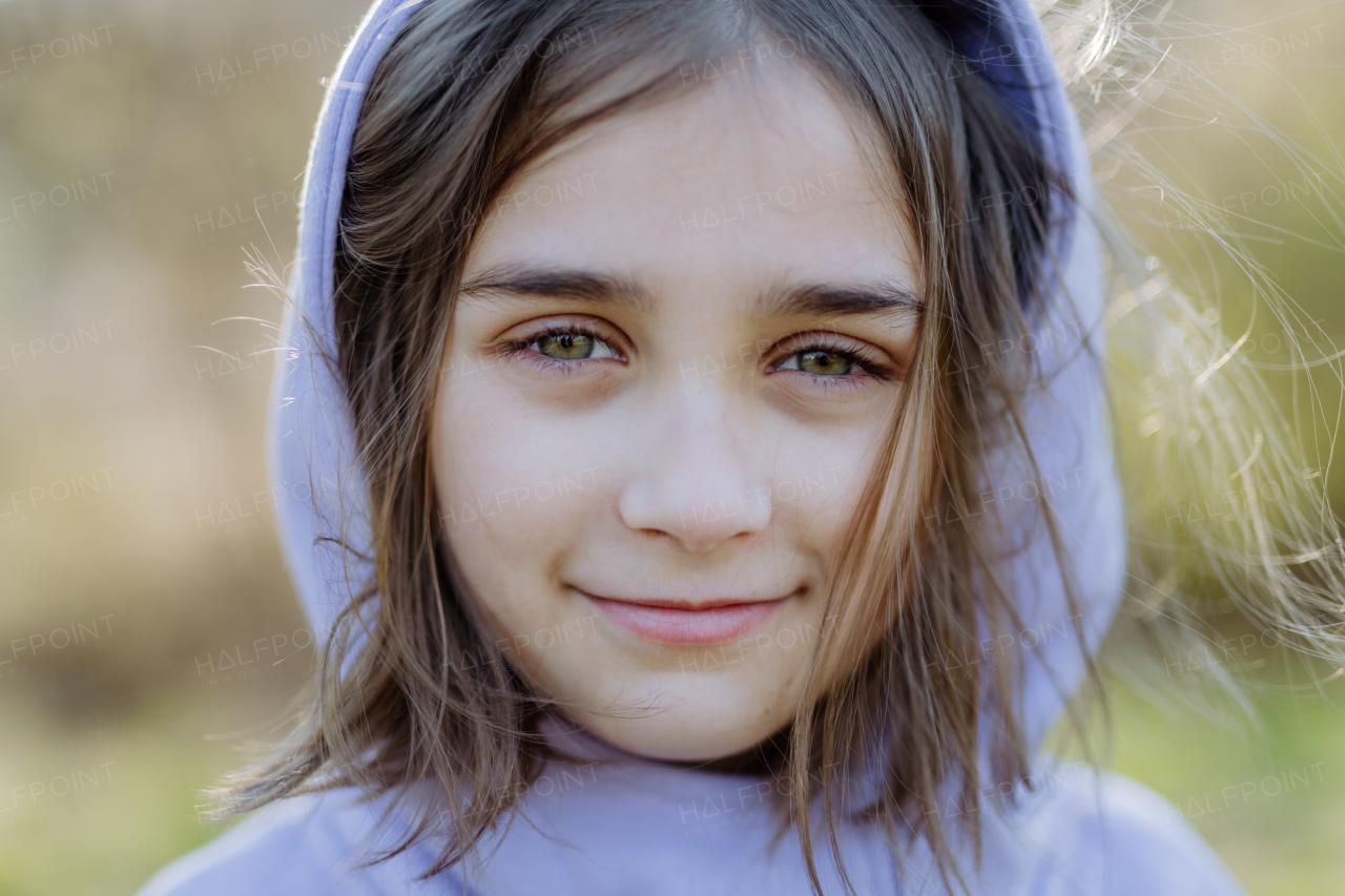 Portrait of pretty child girl standing in summer park looking in camera smiling happily.