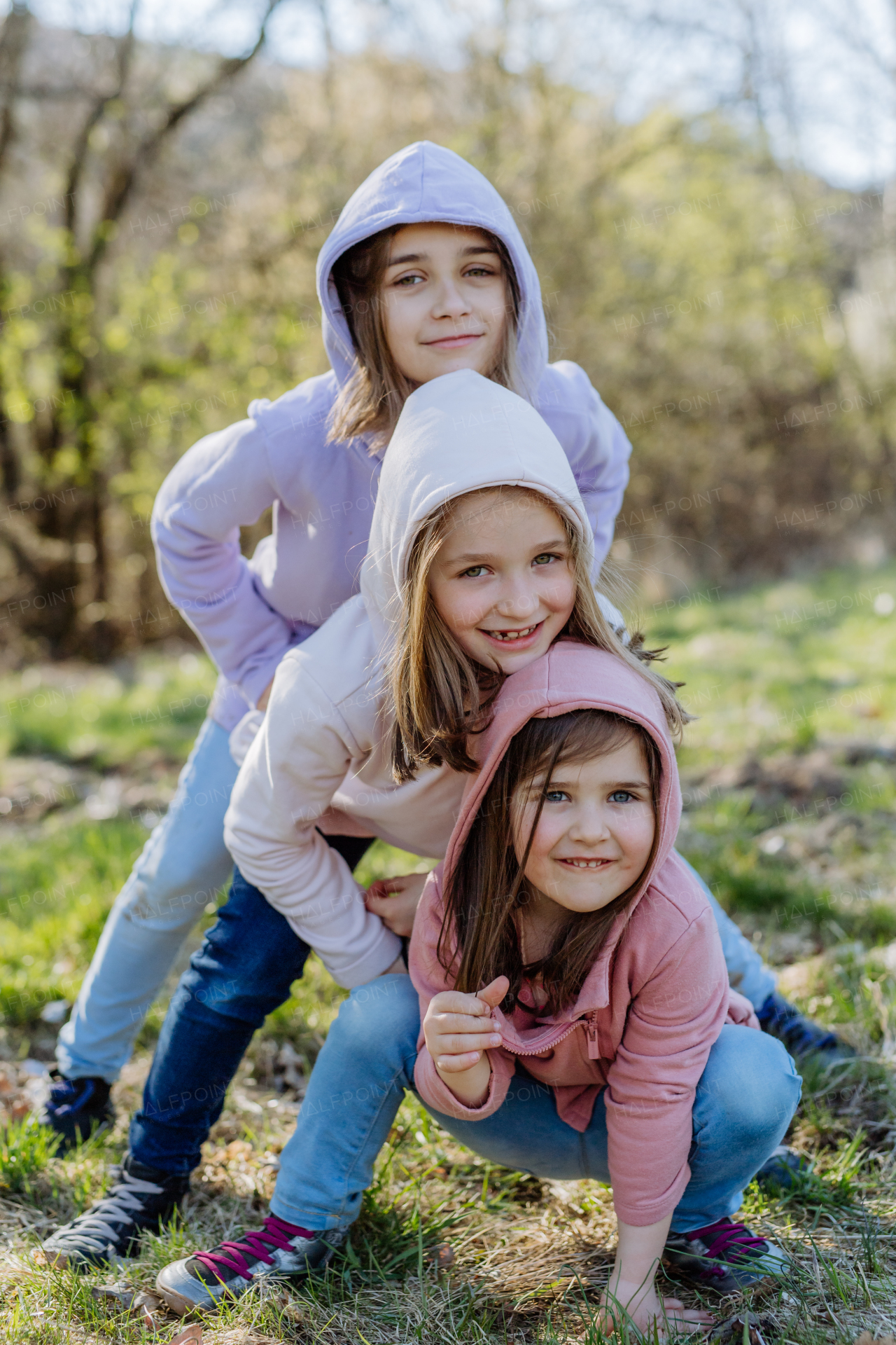 Three little sisters looking at a camera in spring nature together.