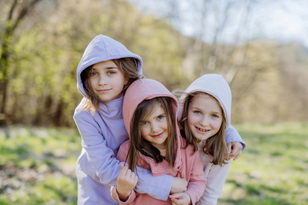 Three little sisters looking at a camera in spring nature together.