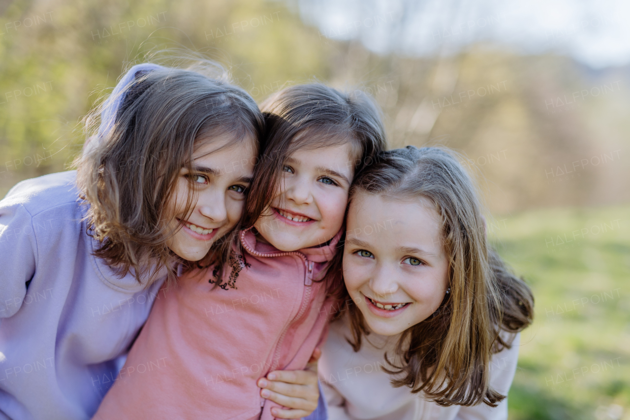 Three little sisters looking at a camera in spring nature together.