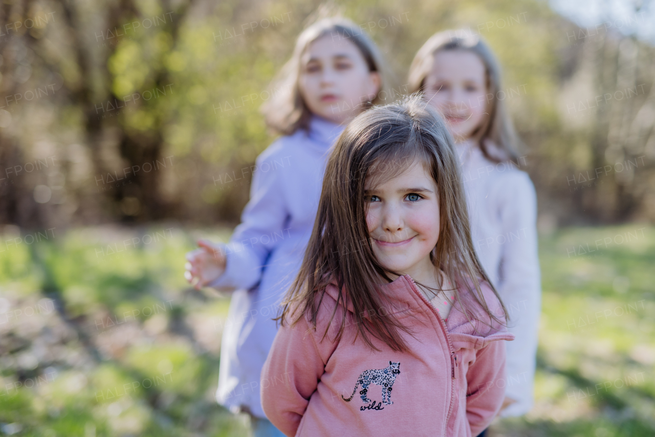 Three little sisters looking at a camera in spring nature together.