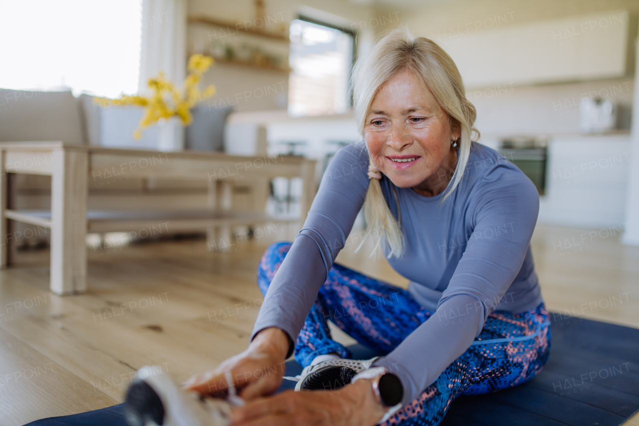 A fit senior woman doing stretching exercise at home, active lifestyle concept.