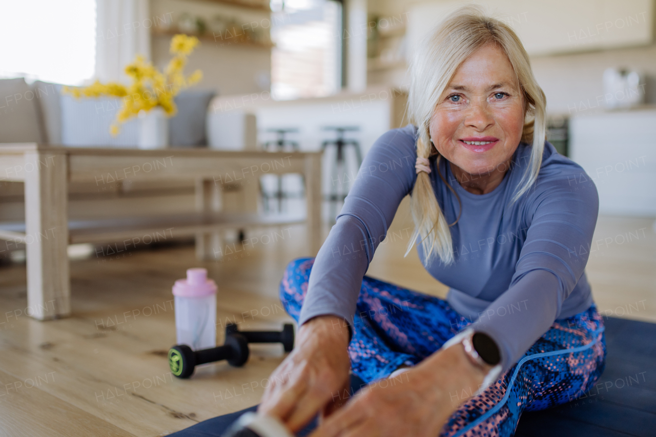 A fit senior woman doing stretching exercise at home, active lifestyle concept.