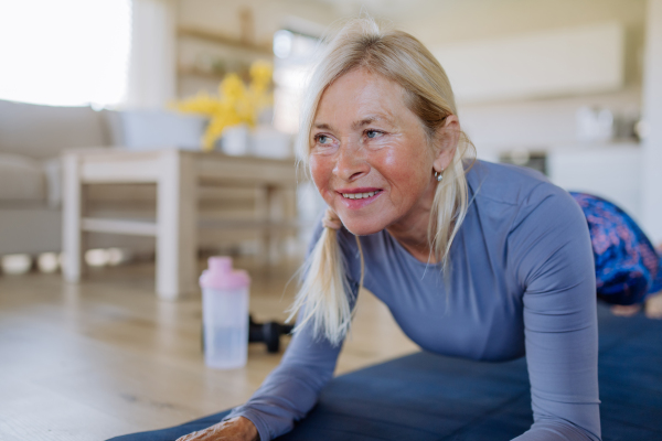 A fit senior woman doing workout exercise at home, active lifestyle concept.