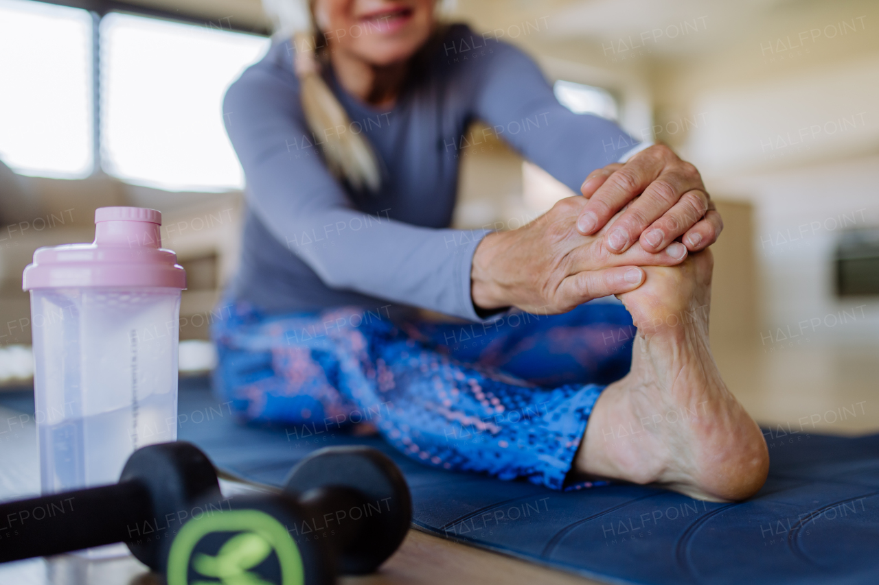 A fit senior woman doing stretching exercise at home, active lifestyle concept.