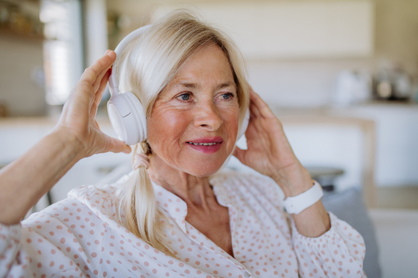 A senior woman with headphones listening to relaxation music at home