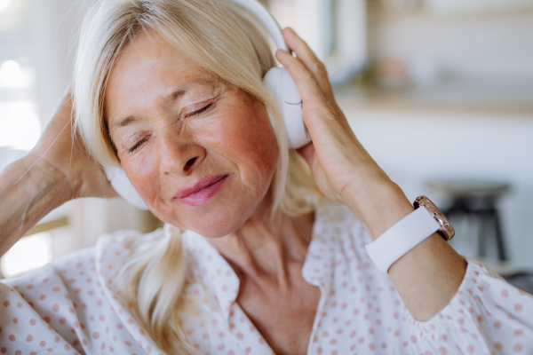 A senior woman with headphones listening to relaxation music at home