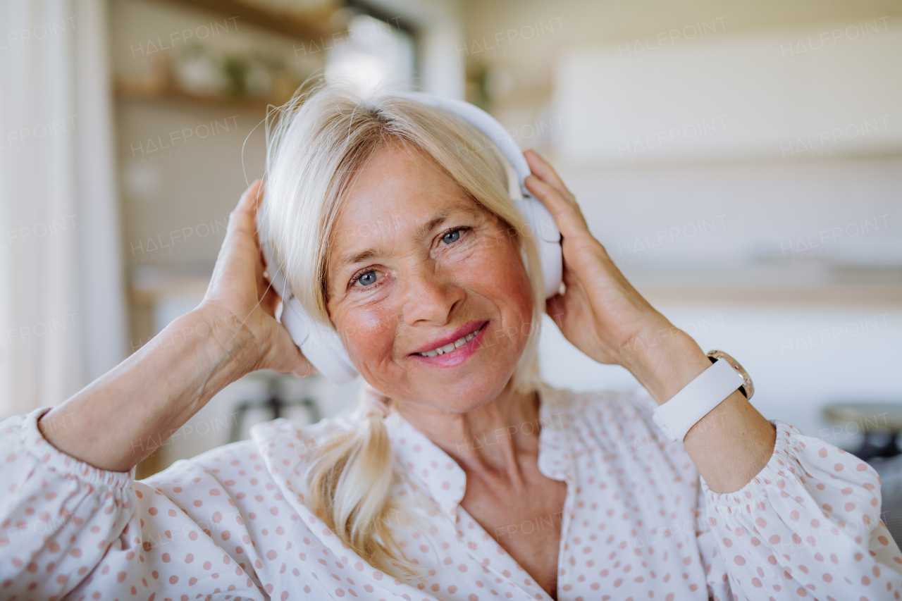 A senior woman with headphones listening to relaxation music at home