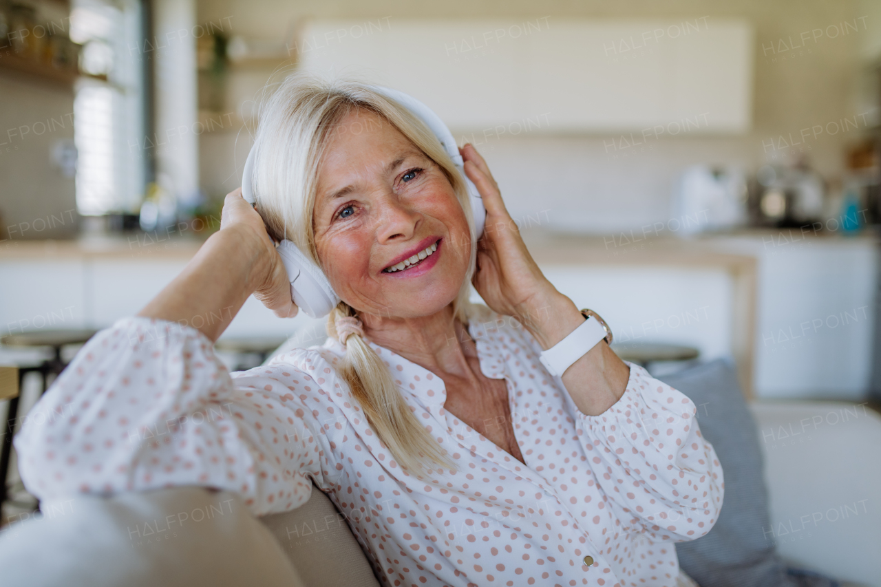 A senior woman with headphones listening to relaxation music at home