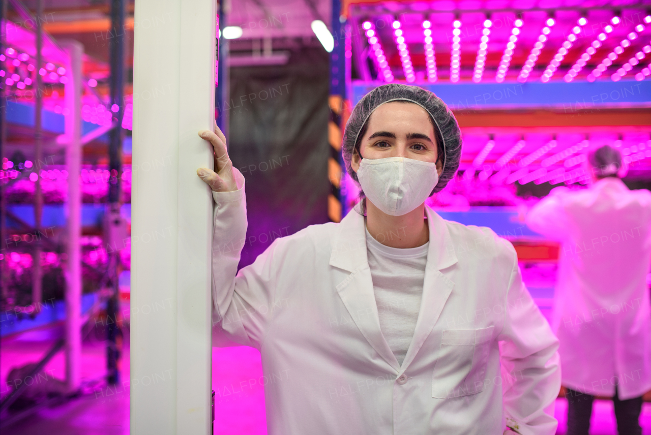 Front view of worker with face mask on aquaponic farm, sustainable business and coronavirus.