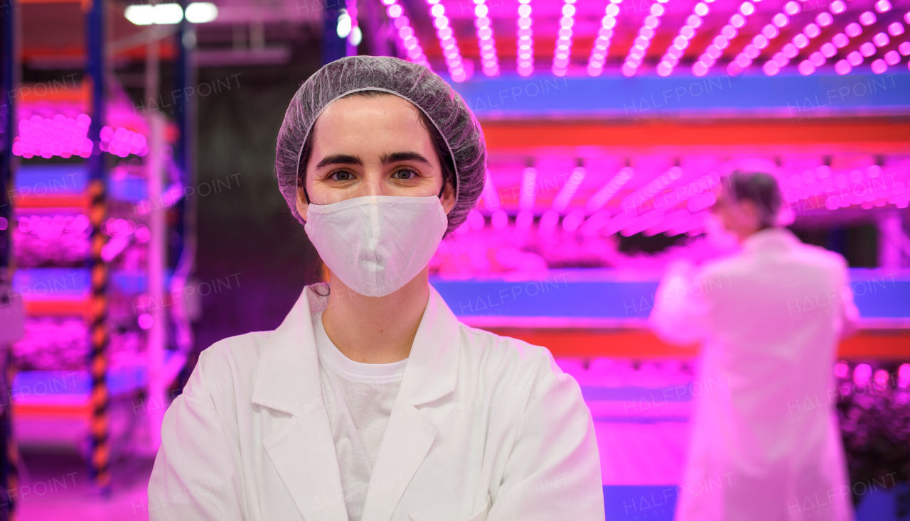 Front view of worker with face mask on aquaponic farm, sustainable business and coronavirus.