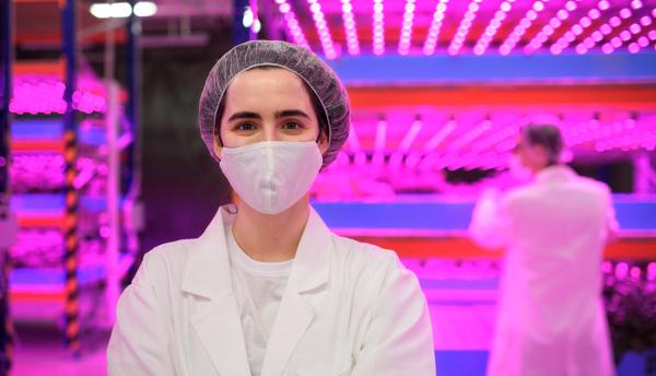 Front view of worker with face mask on aquaponic farm, sustainable business and coronavirus.