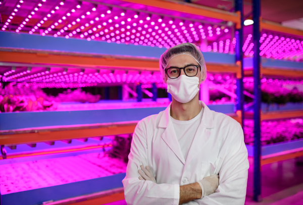 Front view of worker with face mask on aquaponic farm, sustainable business and coronavirus.