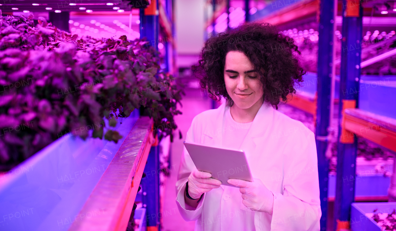 Portrait of worker with tablet on aquaponic farm, sustainable business and artificial lighting.