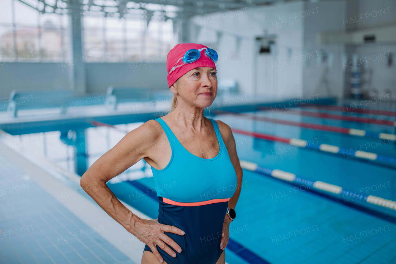 An active senior woman preapring for swim in indoors swimming pool.