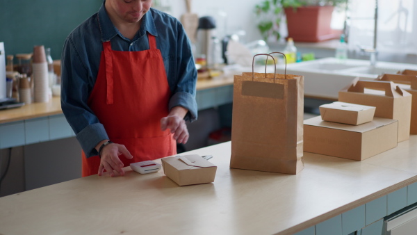 A cheerful young Down Syndrome waiter working in take away restaurant, social inclusion concept.