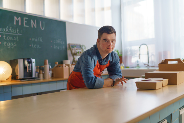 A young Down Syndrome waiter working in take away restaurant, social inclusion concept.