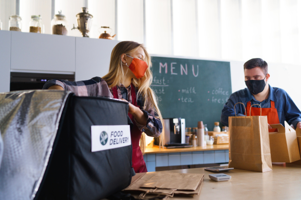 A courier taking meals for delivery from waiter with Down syndrome. Social inclusion concept.