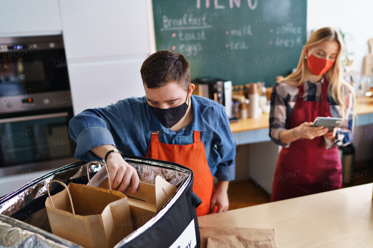 A young Down Syndrome waiter working with colleague in take away restaurant, social inclusion concept.