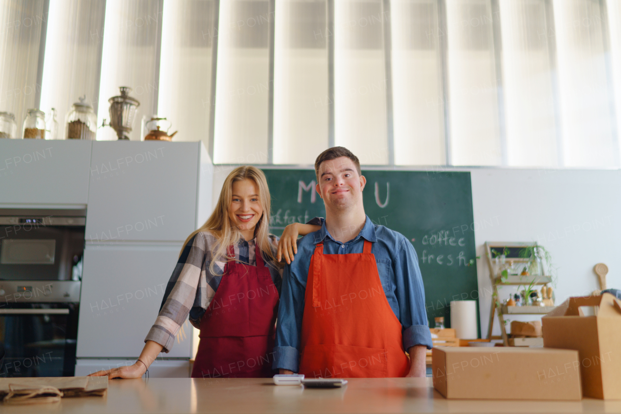 A young Down Syndrome waiter working with colleague in take away restaurant, social inclusion concept.