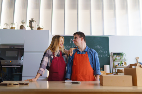 A young Down Syndrome waiter working with colleague in take away restaurant, social inclusion concept.