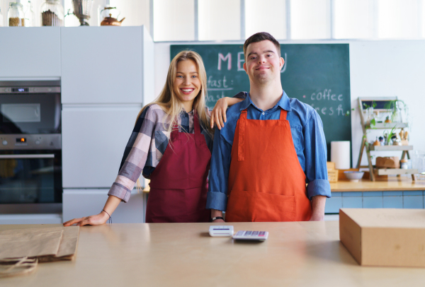 A young Down Syndrome waiter working with colleague in take away restaurant, social inclusion concept.